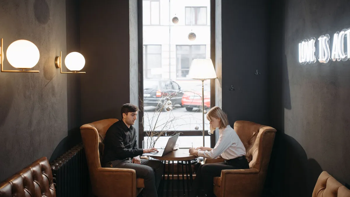 Two colleagues working together in a cozy, modern coffee shop with ambient lighting.