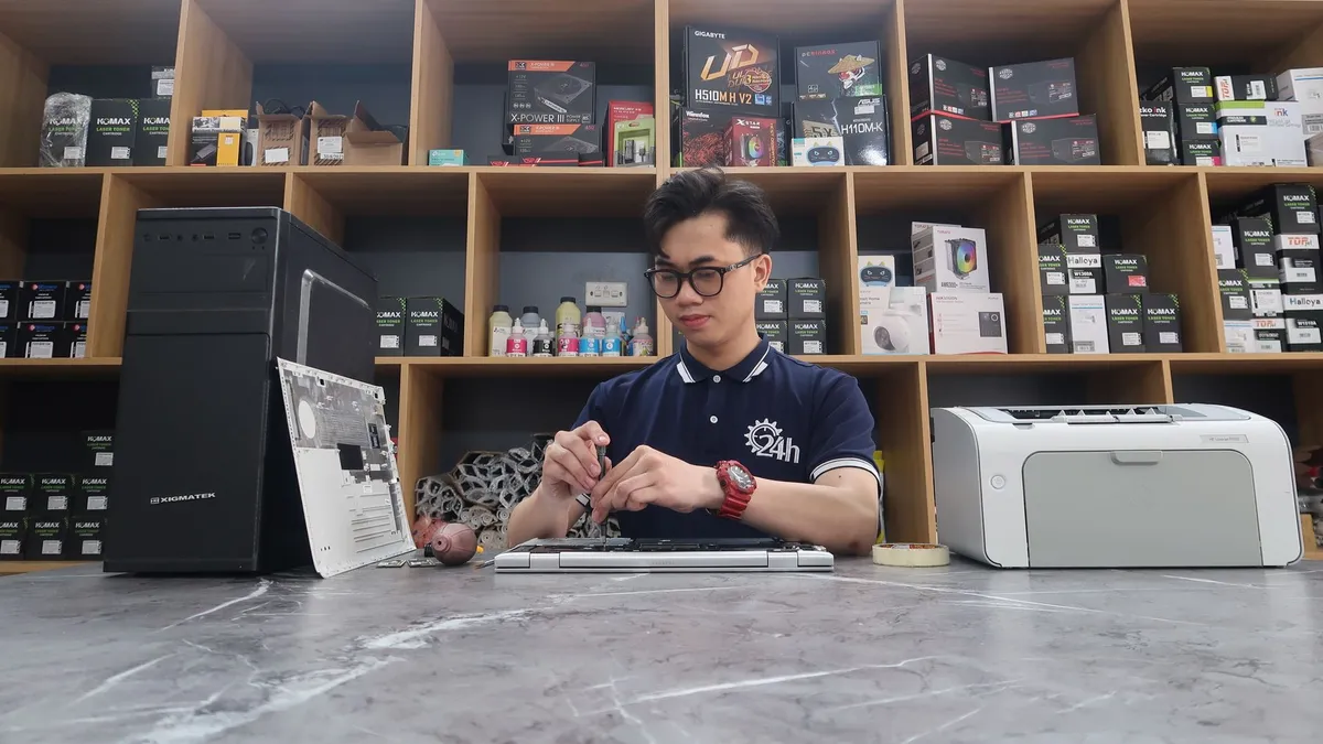 Young technician fixing a computer in a modern electronics store setting.