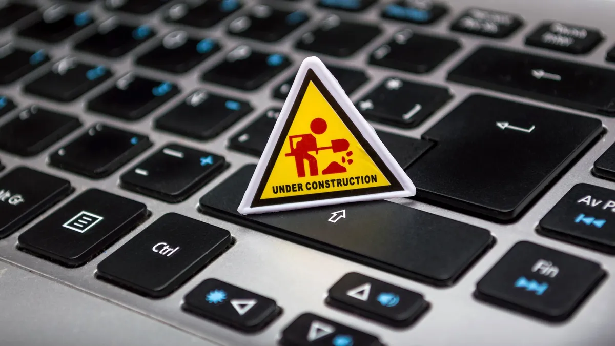 A miniature under construction sign placed on a laptop keyboard symbolizing digital development.