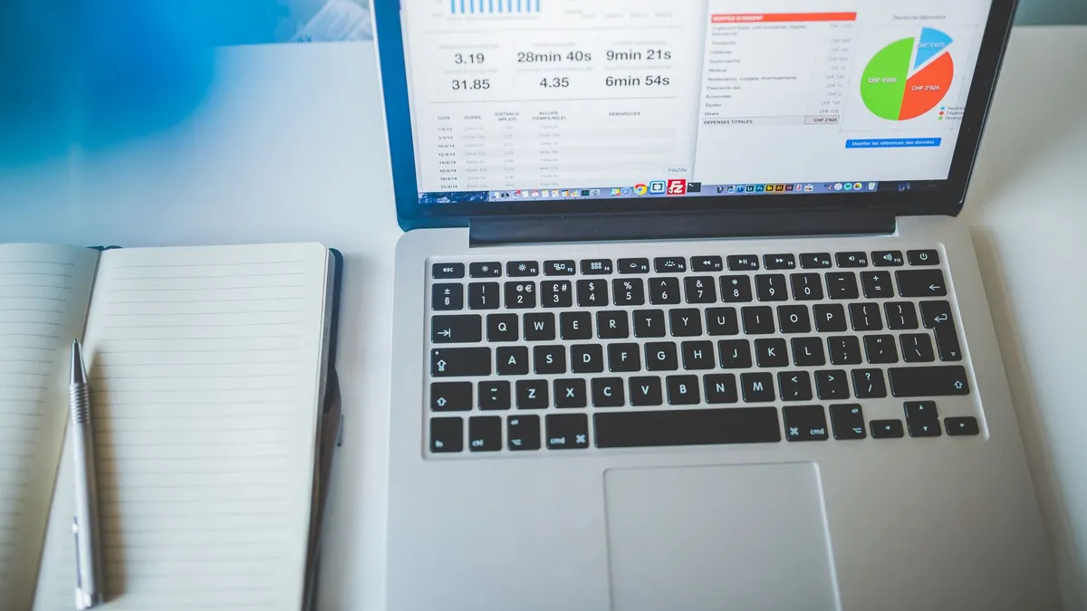 Laptop displaying charts and graphs next to a notebook, ideal for business and tech themes.