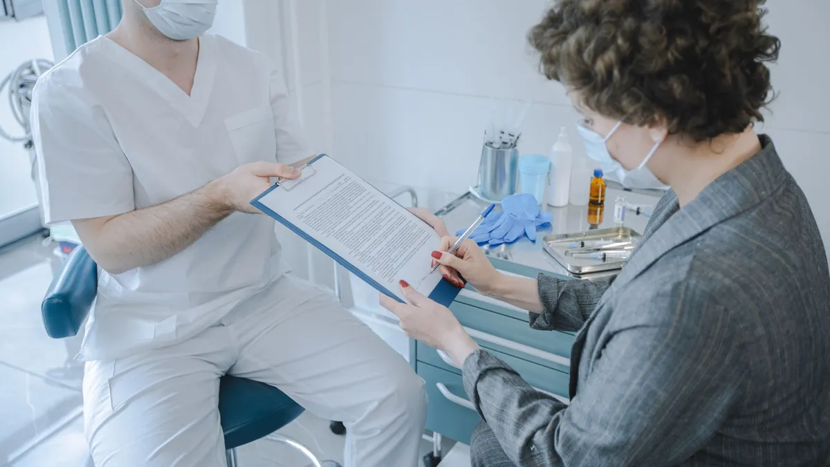 A medical professional and patient reviewing documents in a clinic setting.