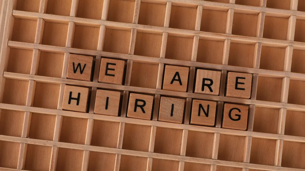 Wooden tiles on a board forming the phrase 'We Are Hiring', ideal for job announcements.