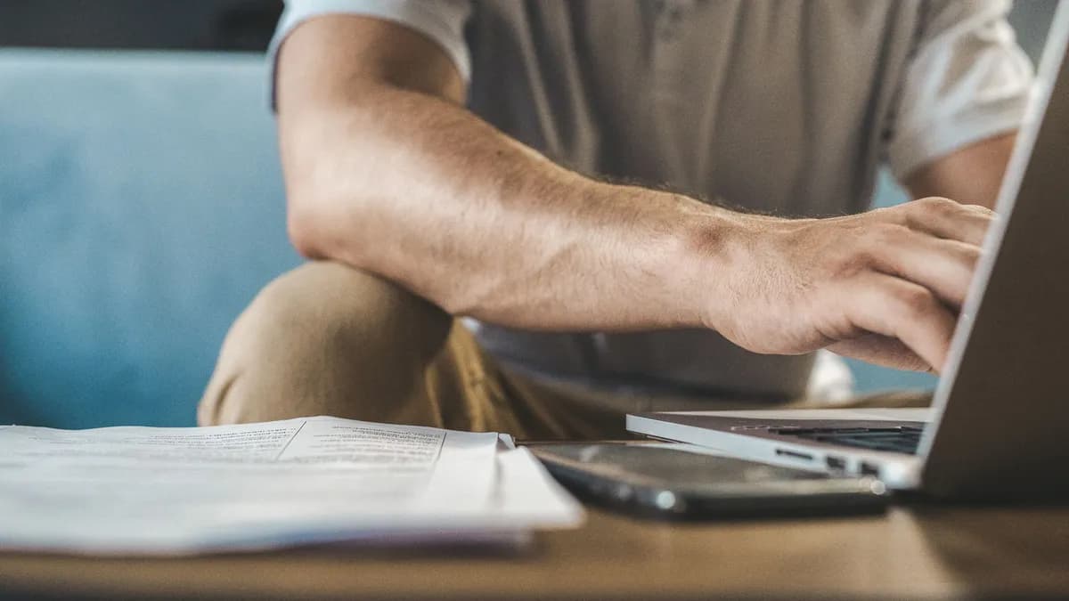 A man typing on a laptop at home, using wireless technology.