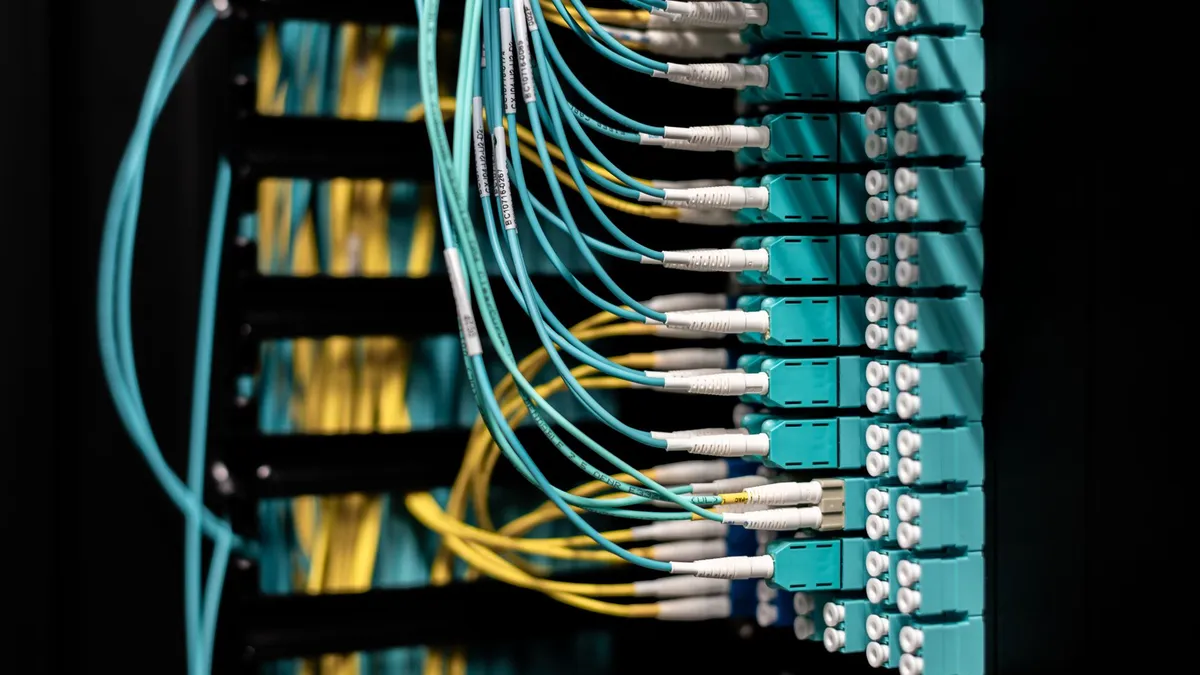 Closeup of electronic device with colorful wires installed in rows in communications room on blurred background in dark studio inside