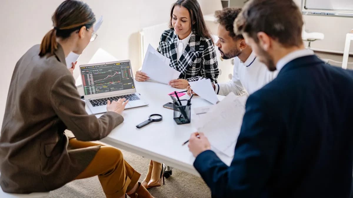 A team of diverse professionals collaborating and analyzing data on a laptop in an office meeting.