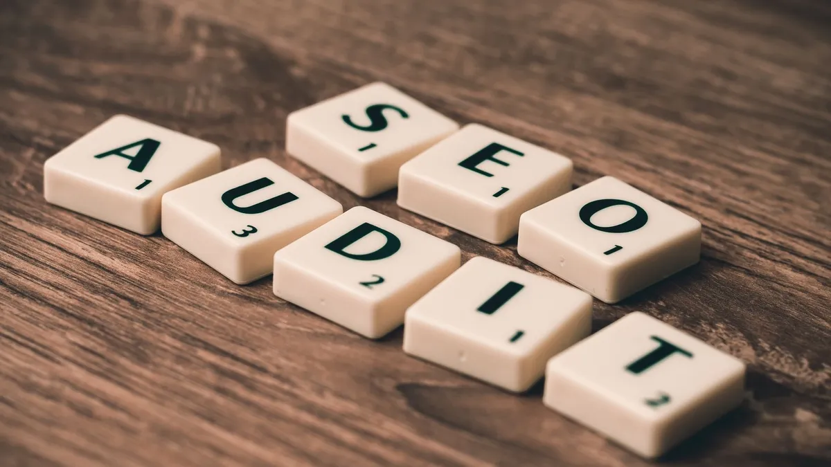 Scrabble tiles spelling SEO Audit on wooden surface, symbolizing digital marketing strategies.