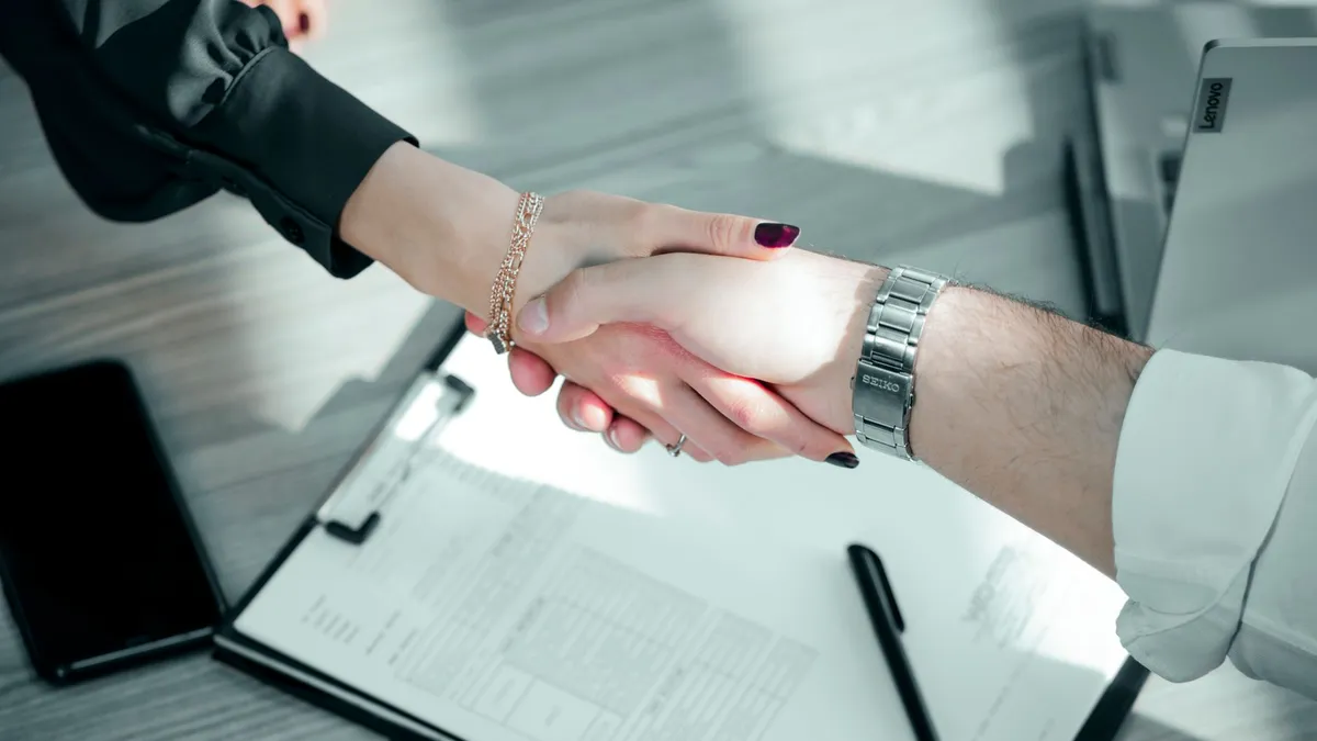 Close-up of a professional handshake over a contract, symbolizing a successful business deal.