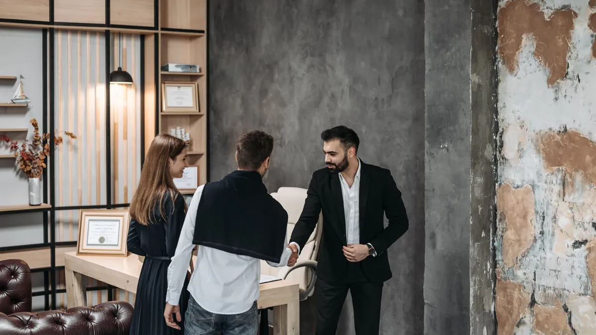 Business professionals discussing in a stylish, modern office setting with a handshake agreement.