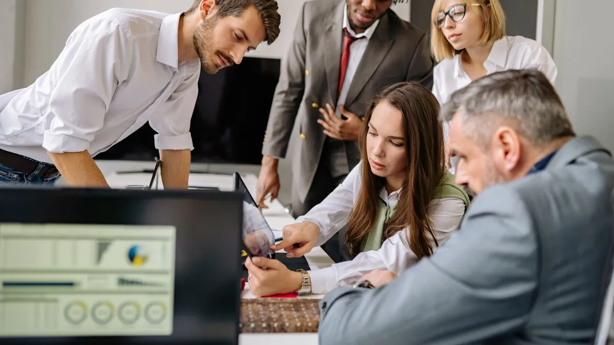 A diverse team engages in a collaborative meeting in a modern office setting, focused on digital analysis.