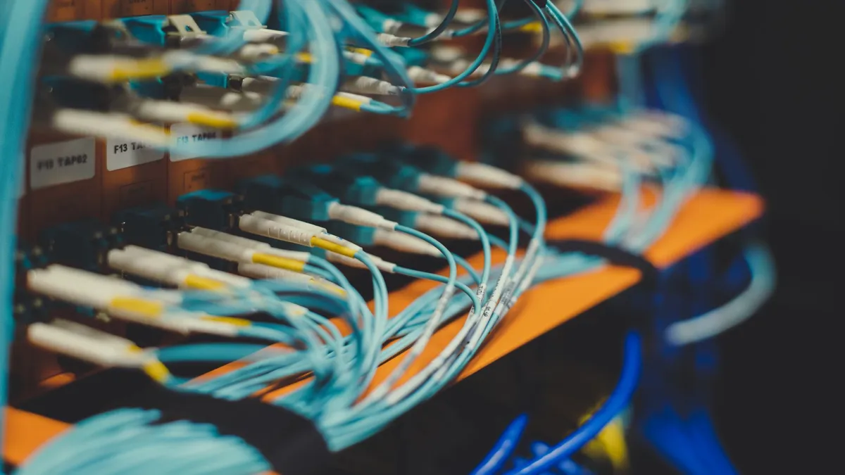 Closeup of many cables with blue wires plugged in modern switch with similar adapters on blurred background in modern studio