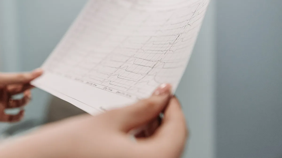 Close-up of a person holding an ECG printout, symbolizing medical diagnosis and health analysis.