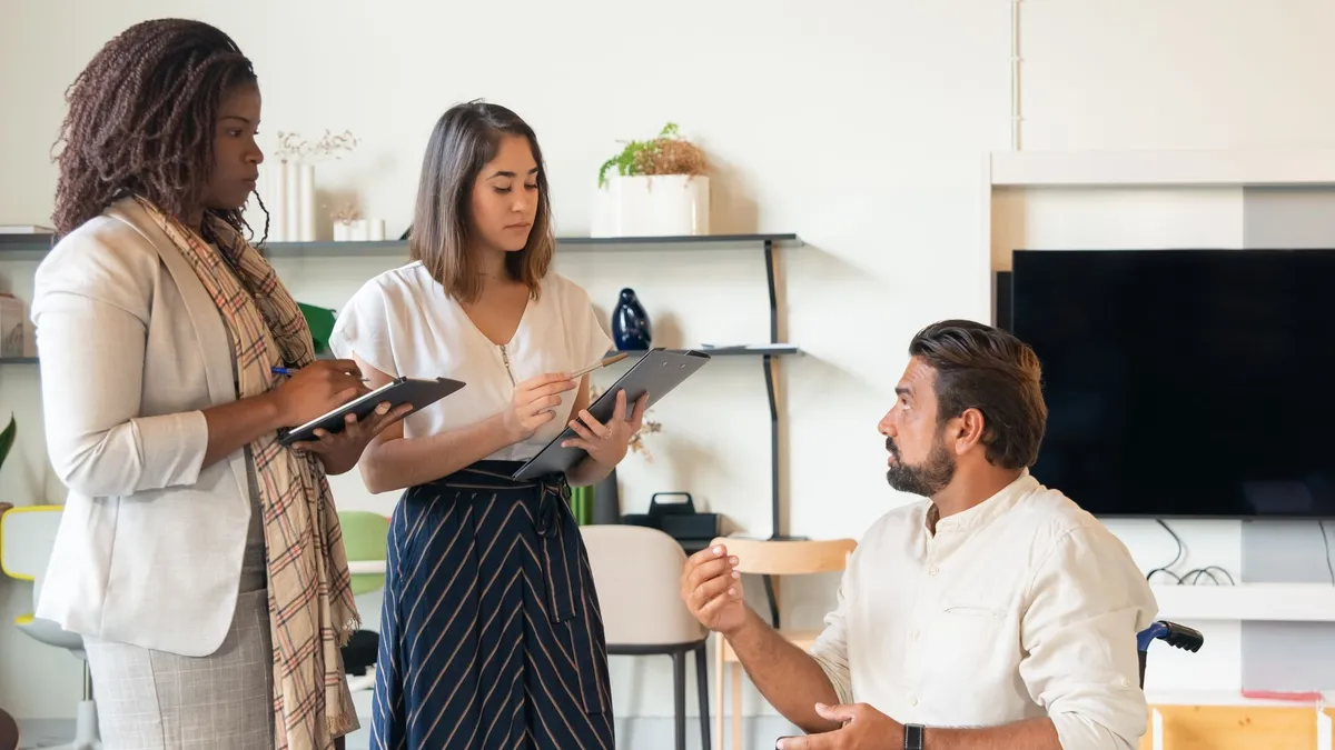 Three coworkers in a contemporary office having a discussion, fostering teamwork and inclusion.
