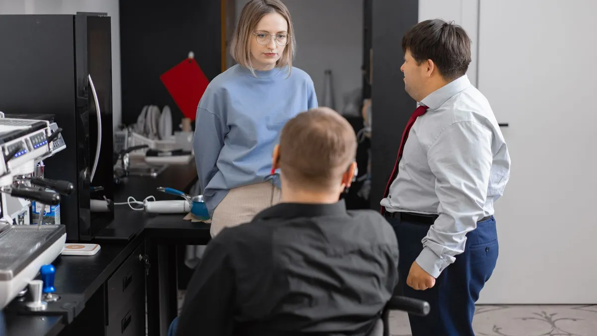Three colleagues having a discussion in a modern office setting, promoting inclusivity and teamwork.