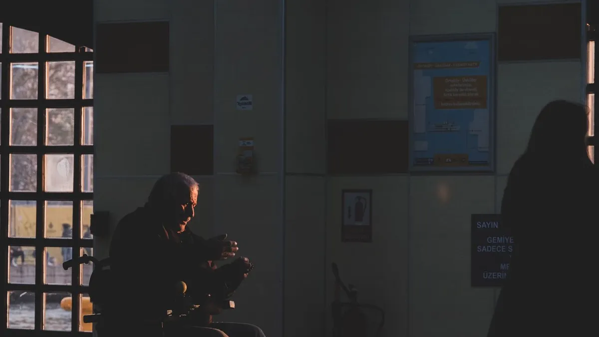 Silhouette of a person in a wheelchair inside a hospital corridor during sunset.