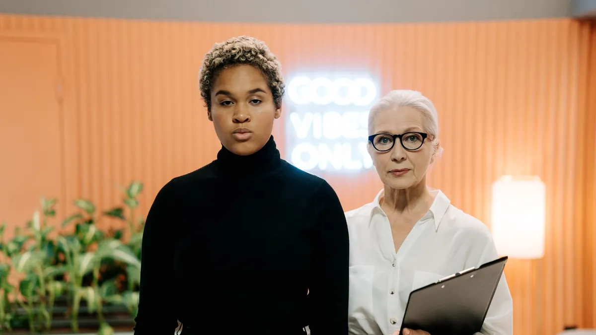 Two diverse women standing together in a contemporary office environment with professional attire.