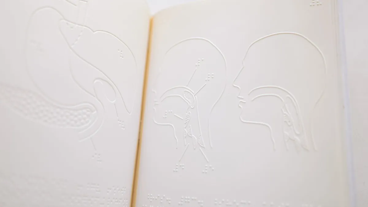 Detailed close-up of embossed anatomy diagrams on an open braille book page.