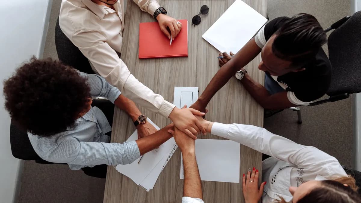 Overhead view of a diverse team placing hands together in a sign of unity during a meeting.