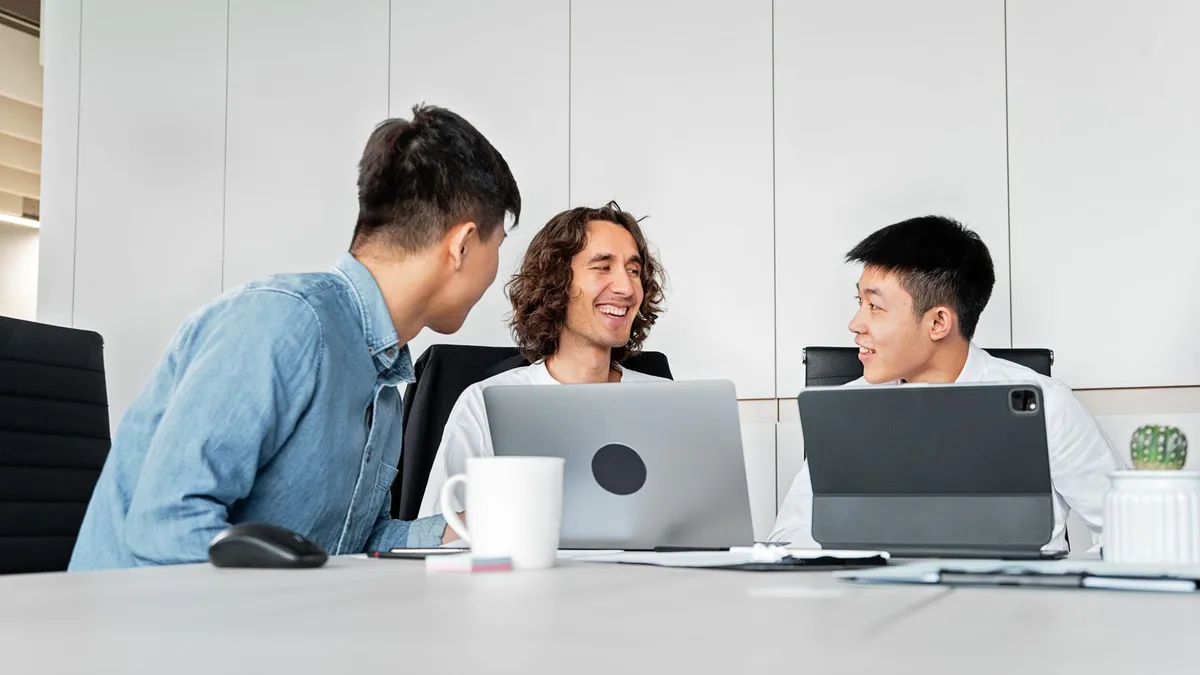A diverse group of colleagues collaborating in a modern office with laptops and tablets.
