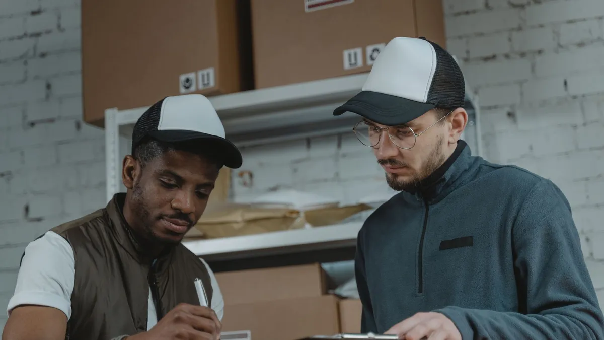 Two couriers working together to process deliveries in a warehouse setting.