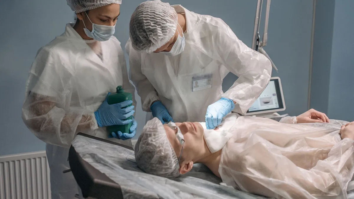Surgeons in sterile gowns performing a procedure on a patient in an operating room setting.