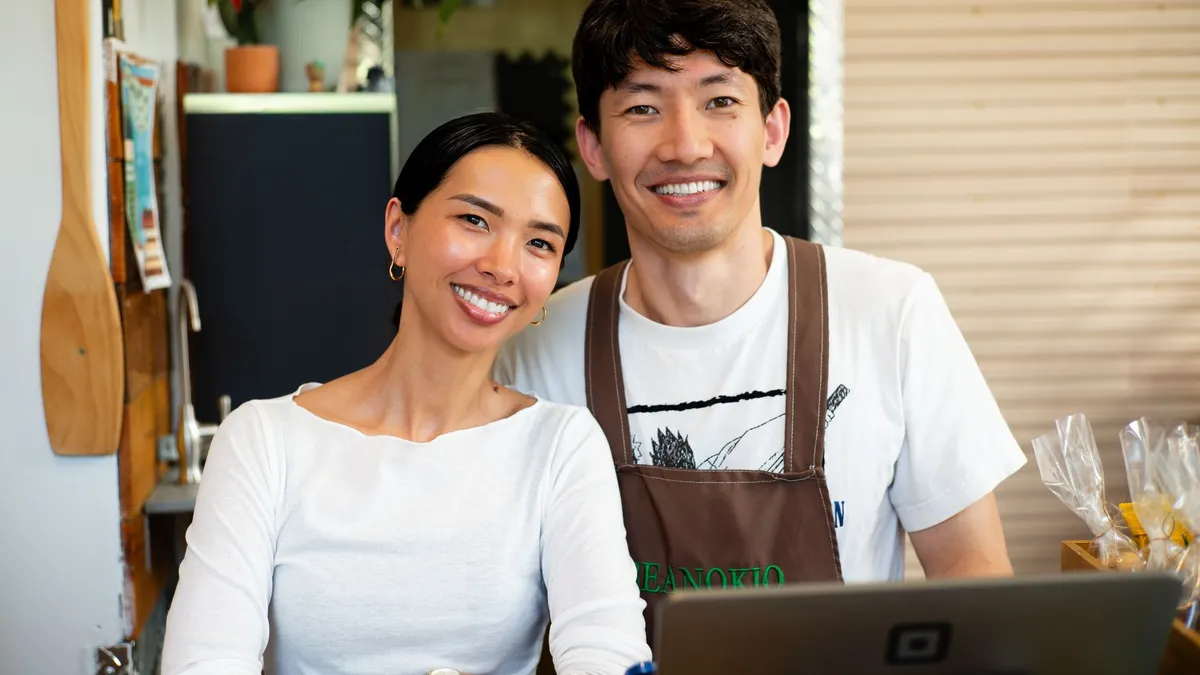 Cheerful cafe owners standing behind the counter in their welcoming coffee shop.