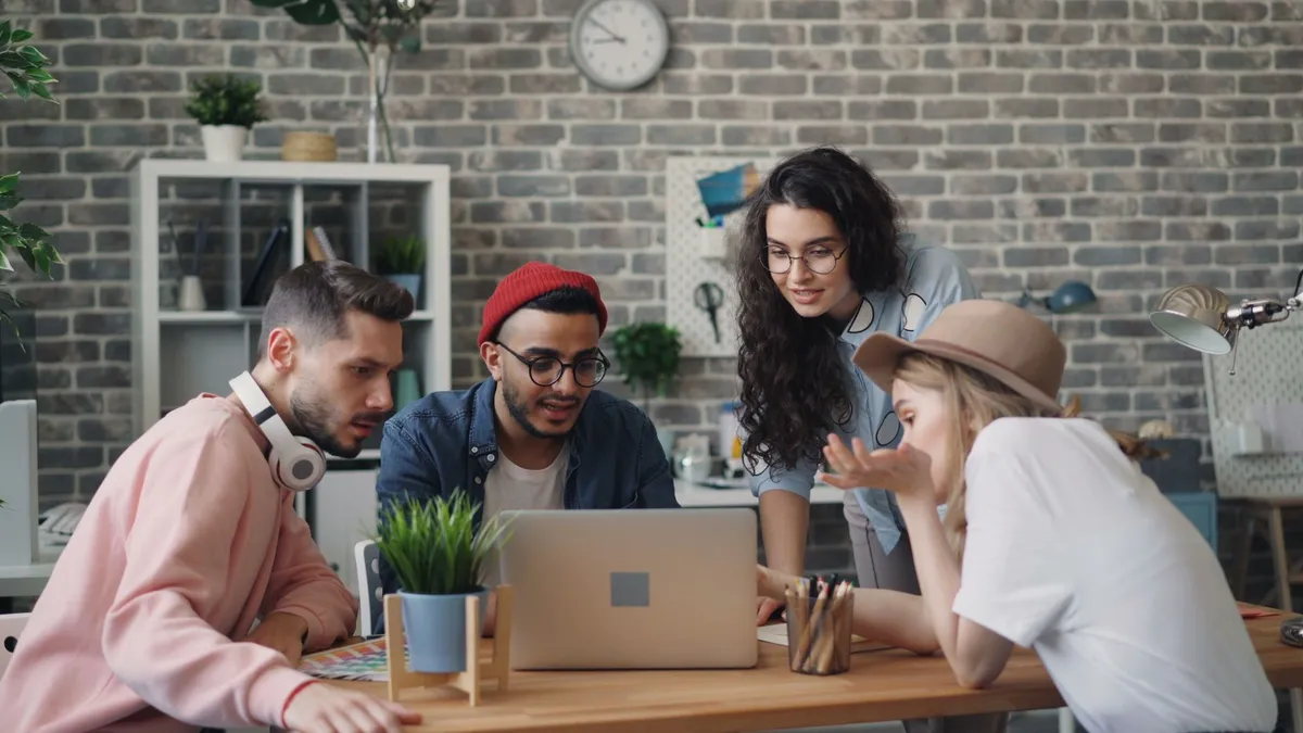 Young professionals collaborate in a modern office setting, focused on a laptop. Creative teamwork at its best.